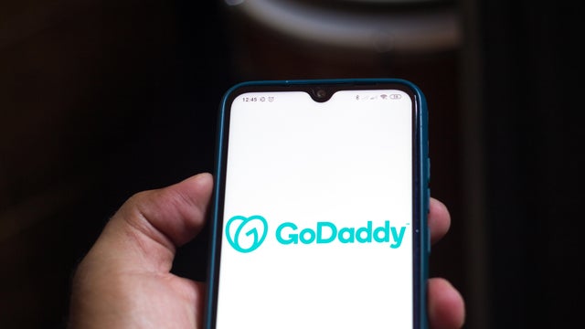 In this photo illustration the GoDaddy logo seen displayed 