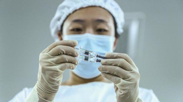 A staff member inspects syringes of COVID-19 inactivated vaccine products at a packaging plant of the Beijing Biological Products Institute Co. 