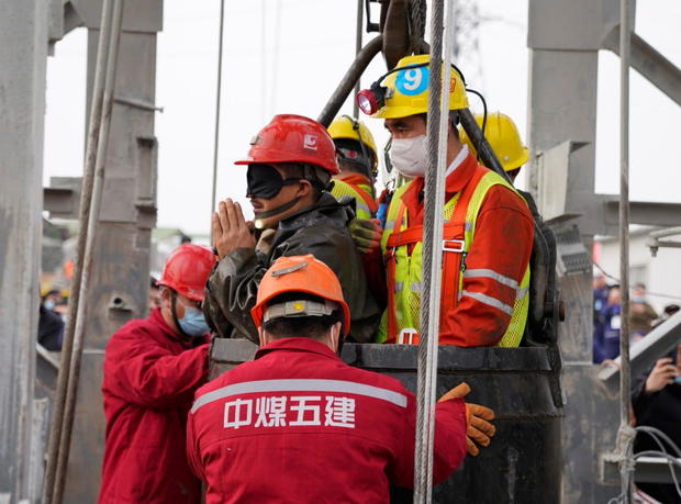 Rescue workers help a miner at the Hushan gold mine after explosion in Qixia, Shandong 