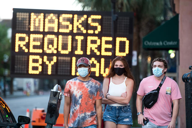 People wearing protective face masks walk along King Street on July 18, 2020, in Charleston, South Carolina. 