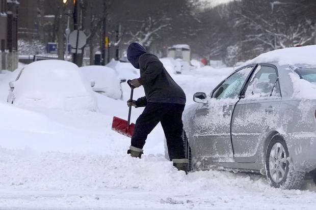 A motorist digs a path for his car February 16, 2021, to enter an unplowed side street in the Bronzeville neighborhood of the South Side of Chicago. 