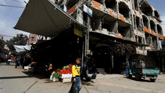 A boy walks past shops in Douma 