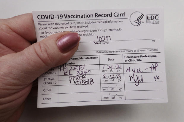 Patient holding Covid 19 vaccinated record card 