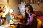 Student working at desk in bedroom at night 