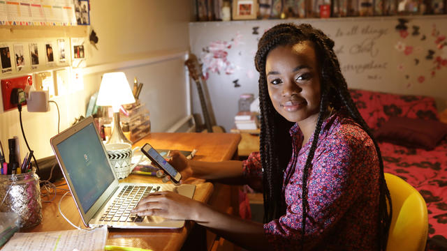 Student working at desk in bedroom at night 