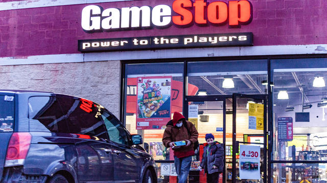 Man and child wearing face masks leave Gamestop store. 