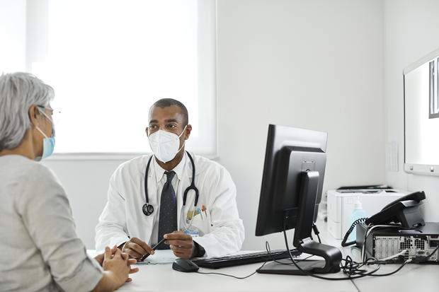 face mask Doctor discussing with patient during pandemic 