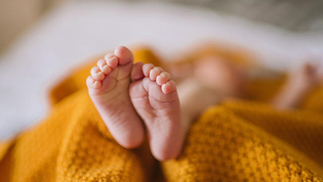 Tiny newborn baby feet in a yellow blanket 