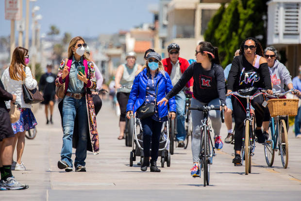 A mix of masked and non-masked people enjoy The Strand path, in Hermosa Beach, California 