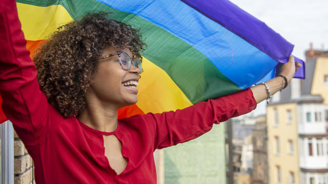 Young lady waving a gay pride flag in support of Gay Pride 