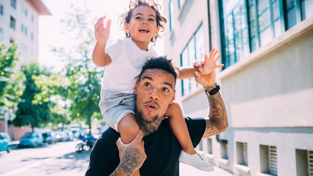 Father and son playing piggyback ride on sidewalk 