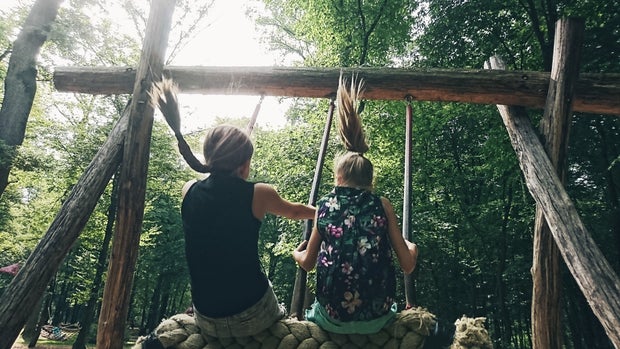 Two girls playing on a rope swing at a playground