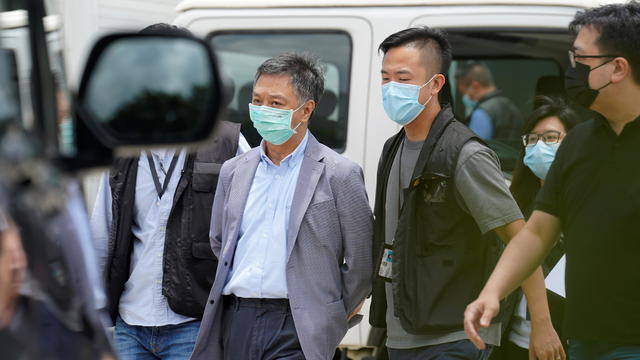 Police officers from the national security department escort Chief Operating Officer Chow Tat-kuen from the offices of Apple Daily and Next Media in Hong Kong 