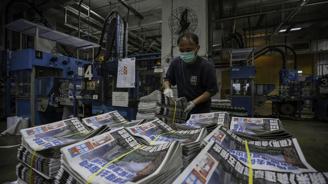 An employee stacks freshly printed papers onto a pallet in 