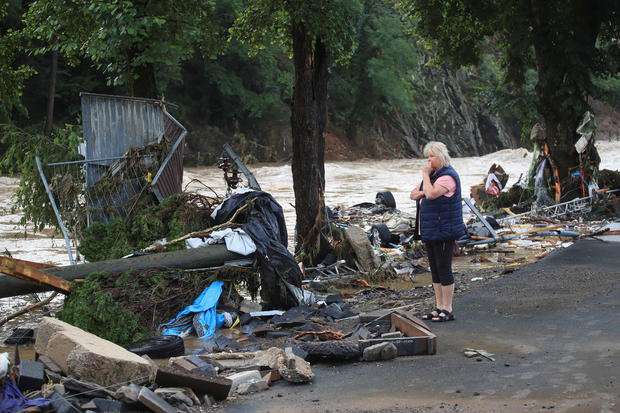 A woman looks at debris brought by the flood next to the Ahr river in Schuld 