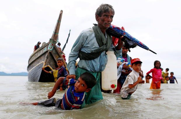 FILE PHOTO: A Rohingya refugee man pulls a child as they walk to the shore after crossing the Bangladesh-Myanmar border by boat through the Bay of Bengal in Shah Porir Dwip 