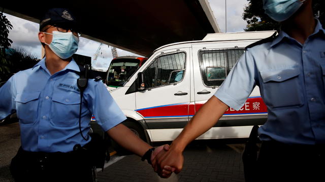 FILE PHOTO: Police officers escort a prison van which is carrying Tong Ying-kit, the first person charged under the new national security law, as he leaves West Kowloon Magistrates' Courts, in Hong Kong 