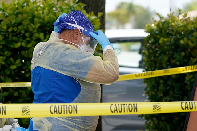 A health care worker with Nomi Health puts on a protective face shield while working at a Miami-Dade County COVID-19 testing site July 26, 2021, in Hialeah, Florida. 