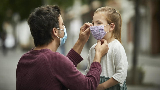 Father Putting Face Mask on Daughter 