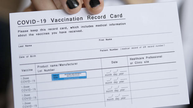Doctor holding COVID-19 Vaccination Record Card. 