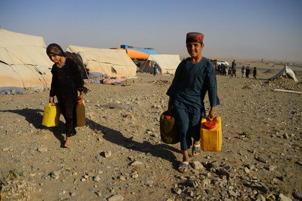 Afghan children carry water containers 