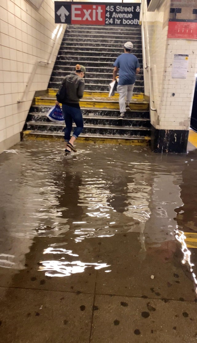 New Yorkers walk through flooded subway station