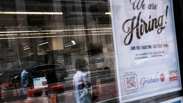 "We are hiring" sign in store window 