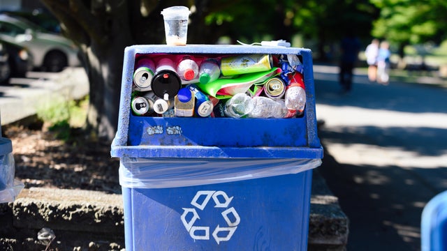 Blue plastic recycling bin full of bottles and cans