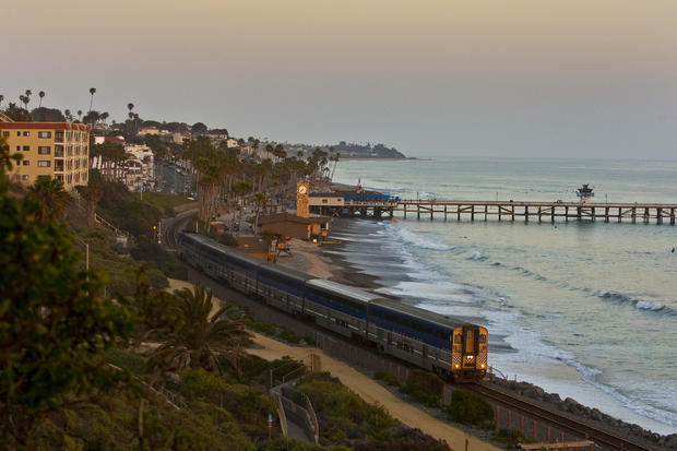 The Amtrak Pacific Surfliner train travels past the the San Clemente pier at sunset. 