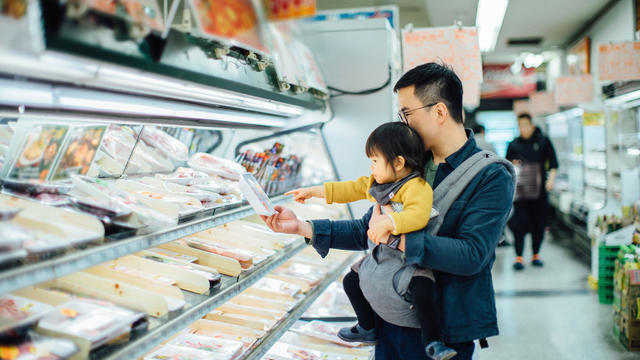 Young Asian father grocery shopping with cute little daughter in supermarket, they are shopping for fresh poultry 