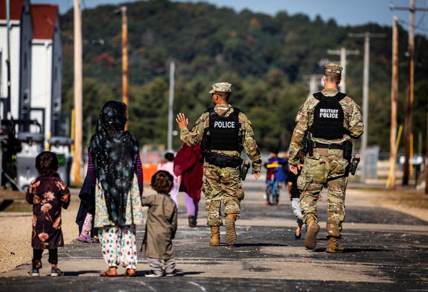 U.S. Military Police walk past Afghan refugees at the Village at Fort McCoy U.S. Army base 