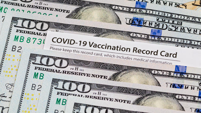 Covid-19 vaccination card and cash money. Covid vaccine lottery, bonus and incentive concept. 