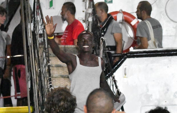 A man waves as he disembarks from the Open Arms rescue ship on the Sicilian island of Lampedusa, southern Italy, Tuesday, Aug. 20, 2019