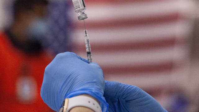 A health worker prepares a syringe with a dose of vaccine 