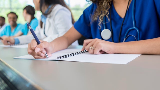 Unrecognizable medical student writes in class workbook 