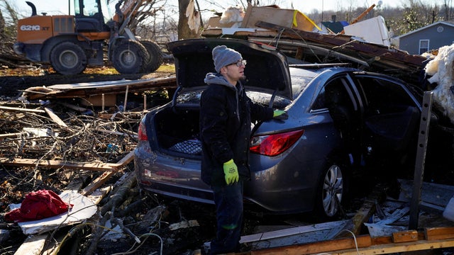 Jeremiah Barker, 37, stands by his destroyed car while looking out at the pile of debris where his home once stood in the aftermath of a tornado in Mayfield, Kentucky, December 13, 2021. 