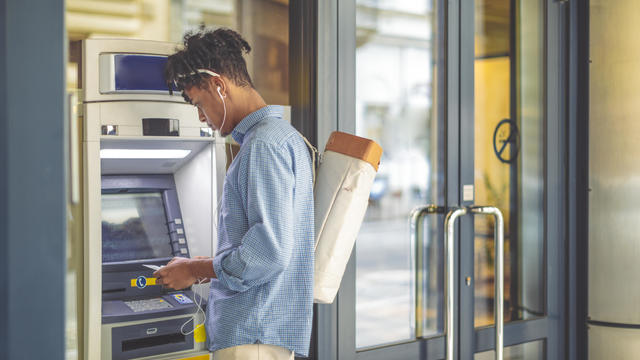 Young man is withdrawing money from an ATM 