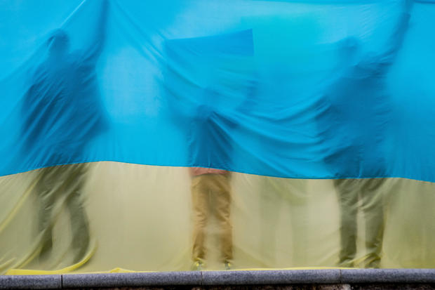 Silhouettes of people are seen through a Ukrainian flag 
