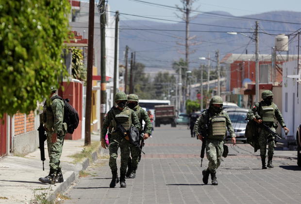 Members of the Mexican army walk near the house where nine people were killed in Atlixco 