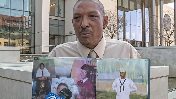 Maurice Peoples Holds Up Photos of His Slain Son Justin 