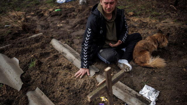 Serhii Lahovskyi mourns next to the grave of his friend Ihor Lytvynenko, in Bucha 