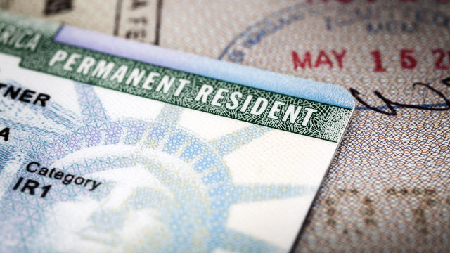 A Green Card lying on an open passport, close-up, full frame 