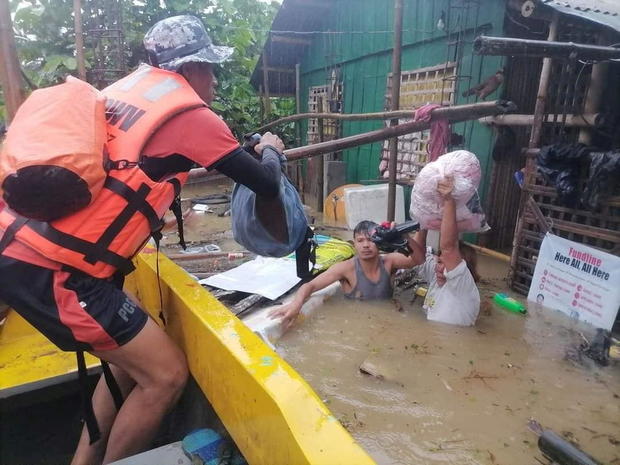 A rescuer assists a man and woman to load their bags onto a rescue boat, after the tropical storm Megi hit, in Capiz Province 