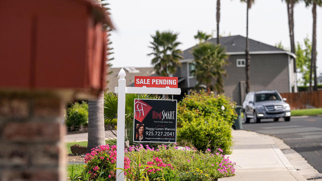 "Sale pending" sign on a palm-tree lined suburban street 