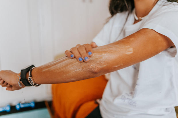 sunscreen medium shot of young woman in casual clothes applying cream on arms 