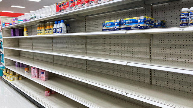 A nearly empty baby formula display shelf is seen at a 