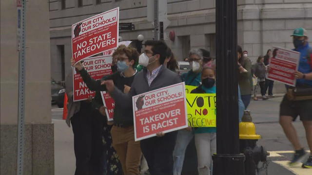 Parents and teachers hold signs opposing receivership 