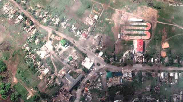 A satellite image shows damaged buildings and a tank on a road, in Lyman 