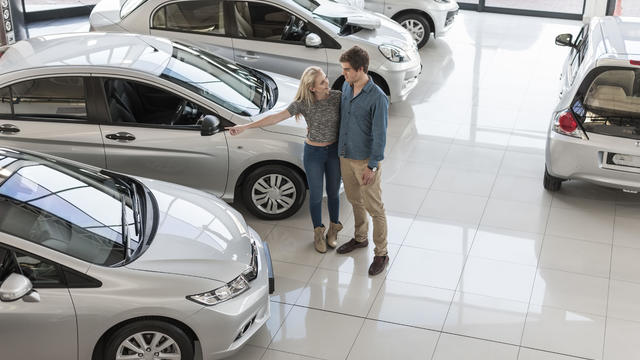 Young couple looking at new cars at car dealership 