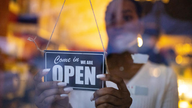 Business owner hanging an open sign at a cafe 